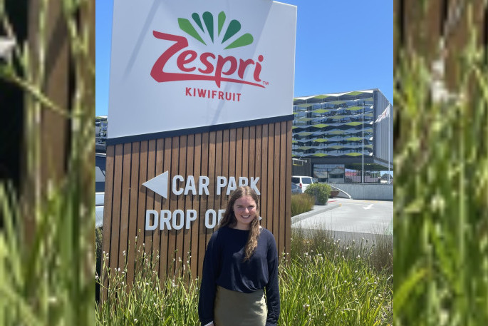 Sarah Wilson standing outside a zespri kiwifruit sign in Te Puke